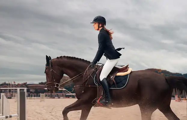 Cavalière montant un cheval sur une piste d’entraînement hippique